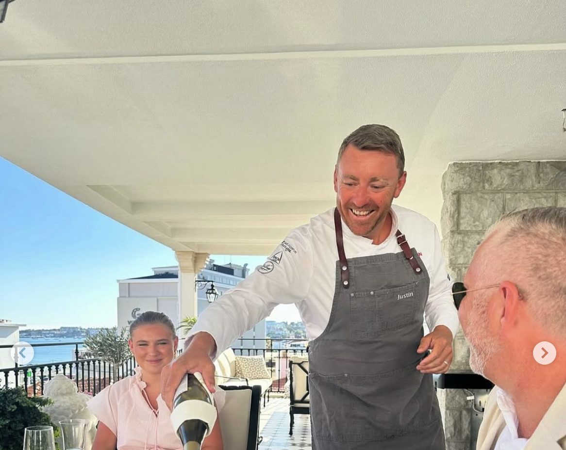 Private chef Justin Jennings serving wine at an outdoor terrace dinner party in Lisbon